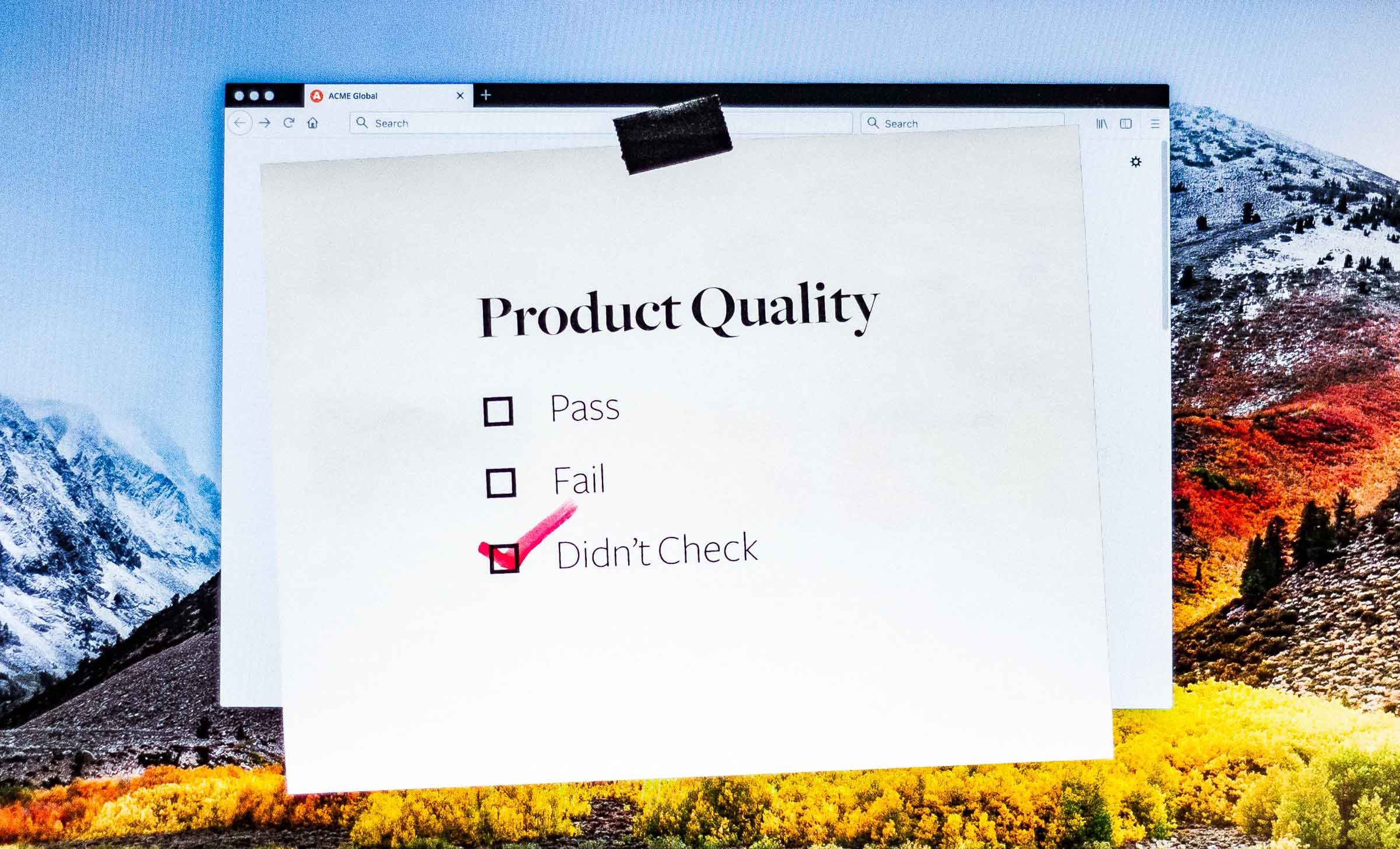 A computer screen with a note taped to the top that reads, "Product Quality" with boxes for "Pass," "Fail," and "Didn't Check." The box "Didn't Check" is marked.