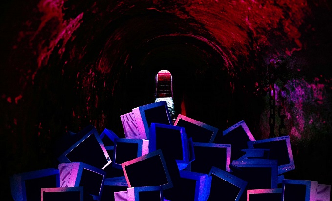 A dark dungeon containing a pile of dimly lit computers.