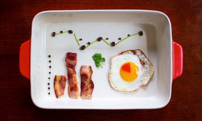 A casserole dish with bacon, an over-easy egg, and a trail of raisins designed to look like different types of graphs.