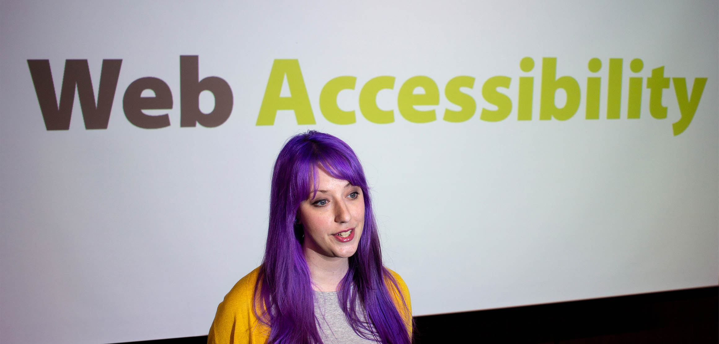 Bekah speaking in front of a projector with the words Web Accessibility.